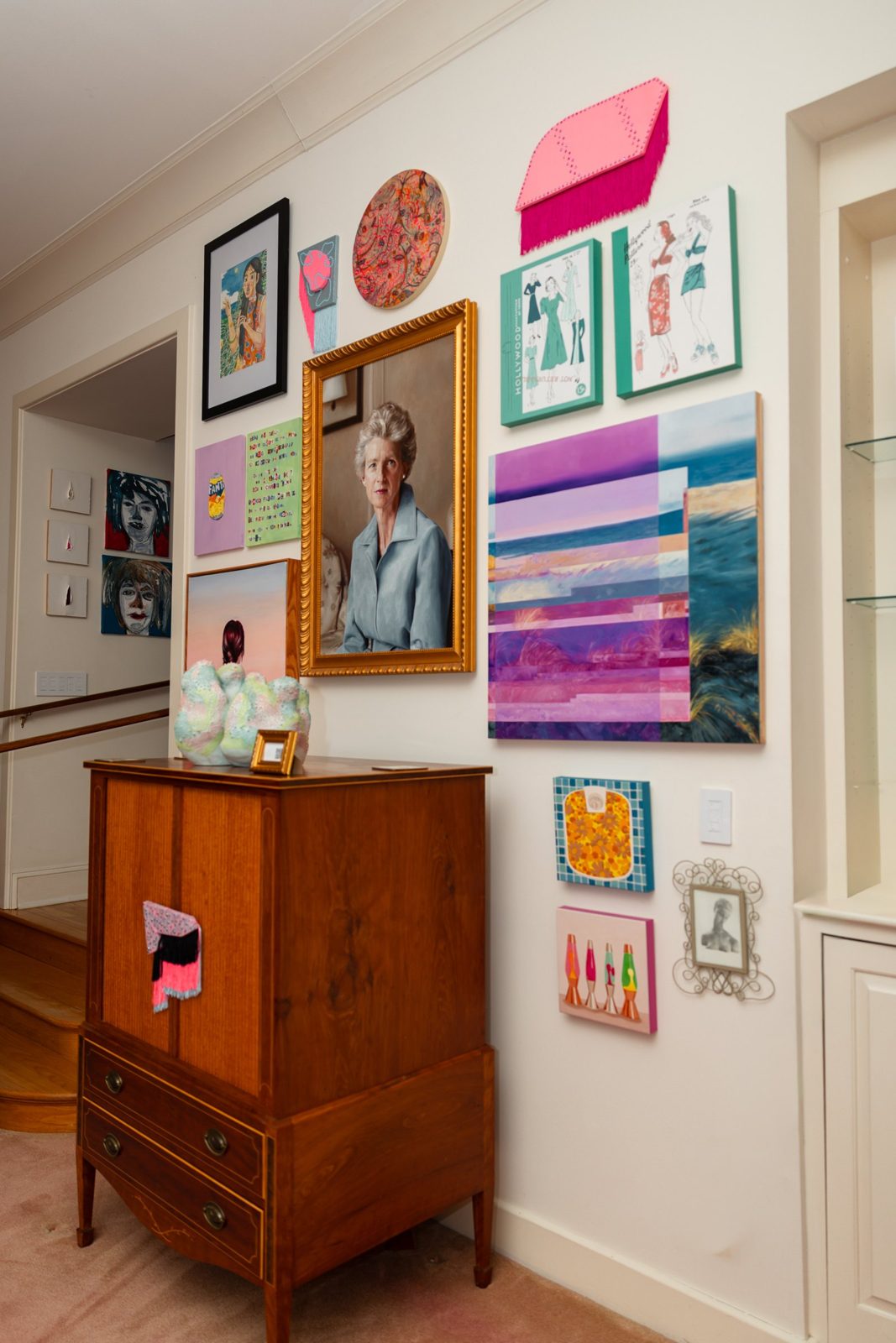 Paintings hung around a wooden cabinet at Girlism