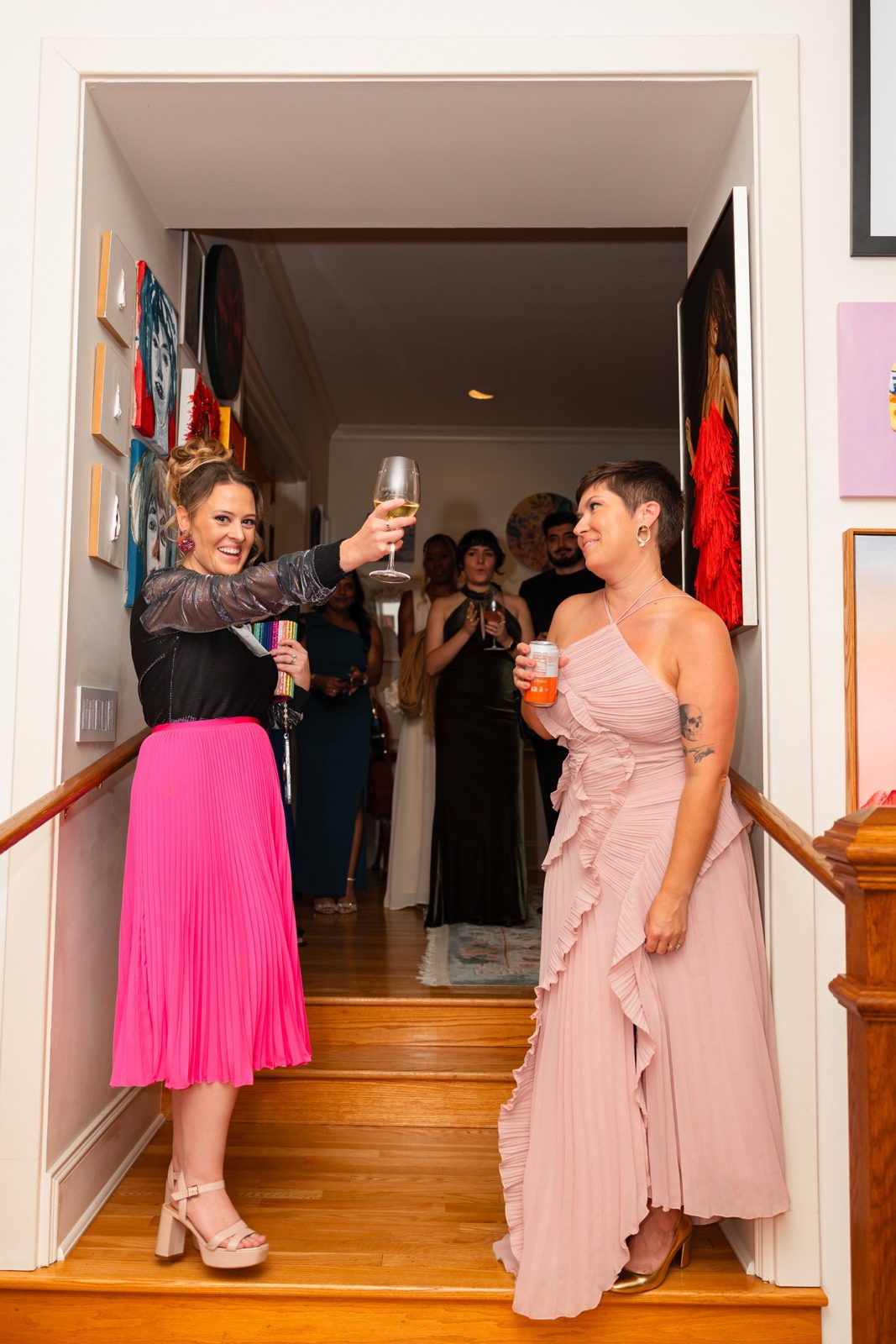 Sarah Jamison and Stephanie Ervin, co-founders, raising a glass on the stairs at Girlism
